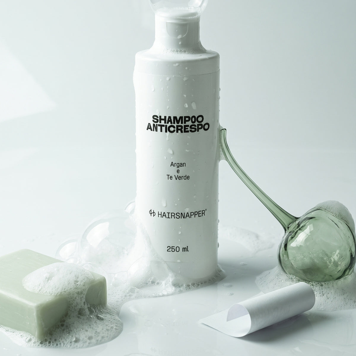 HairSnapper Shampoo Anticrespo 250 ml fra schiuma e bolle di sapone su fondo bianco